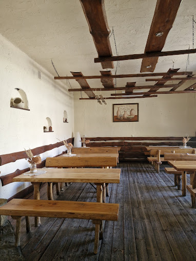 Sala karczmy z drewnianymi stołami i ławami